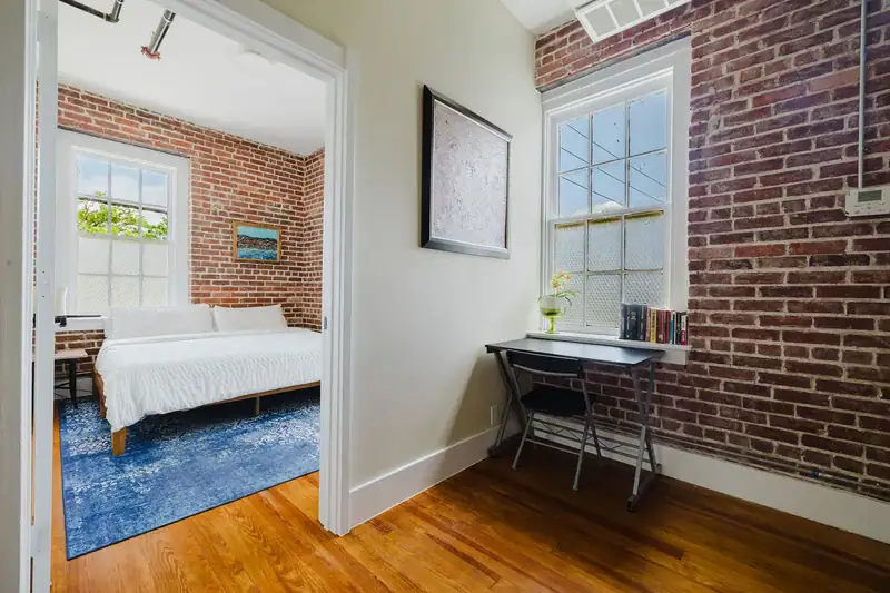 Apt 201 bedroom with exposed brick wall and windows