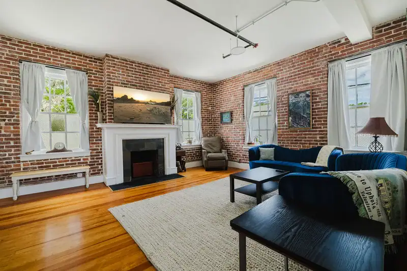 Apt 201 living room with decorative fireplace and brick walls