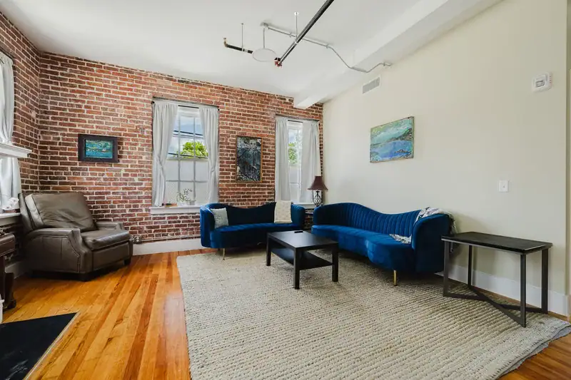 Apt 201 seating area with exposed brick and large windows