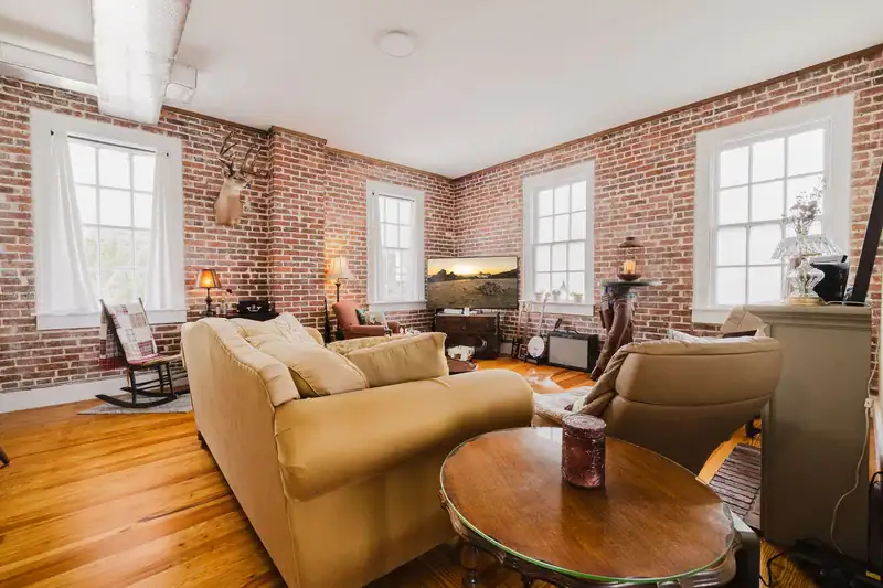Corner of the living room in Apartment 301 with brick walls and windows facing three directions
