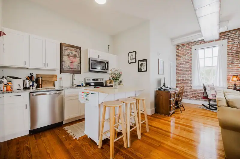 Kitchen in Apartment 301 with white shaker cabinets, stainless dishwasher and range, and a breakfast bar