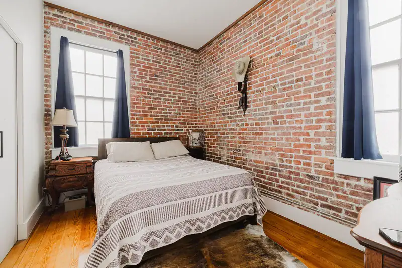 Bedroom in Apartment 301 with exposed brick walls, two windows and hardwood floors
