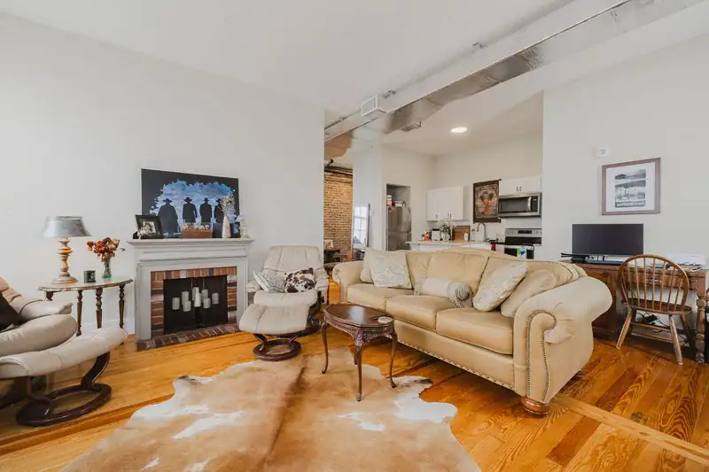 Living area in Apartment 301 with a decorative fireplace and the kitchen beyond