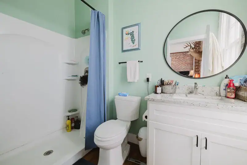 Bathroom in Apartment 301 with a walk-in shower, vanity with stone counter and round mirror