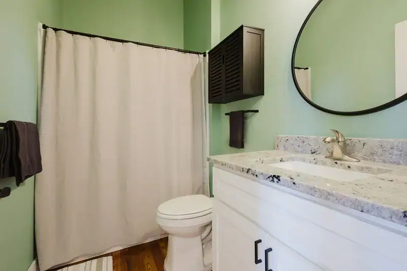 Apartment 303 bathroom vanity with round mirror and walk-in shower