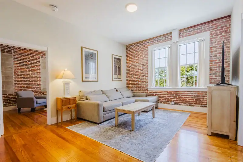 Apartment 303 living room with lamp, sectional sofa and exposed brick