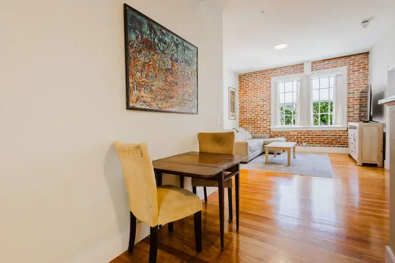 Apartment 303 dining table with the living area and exposed brick beyond