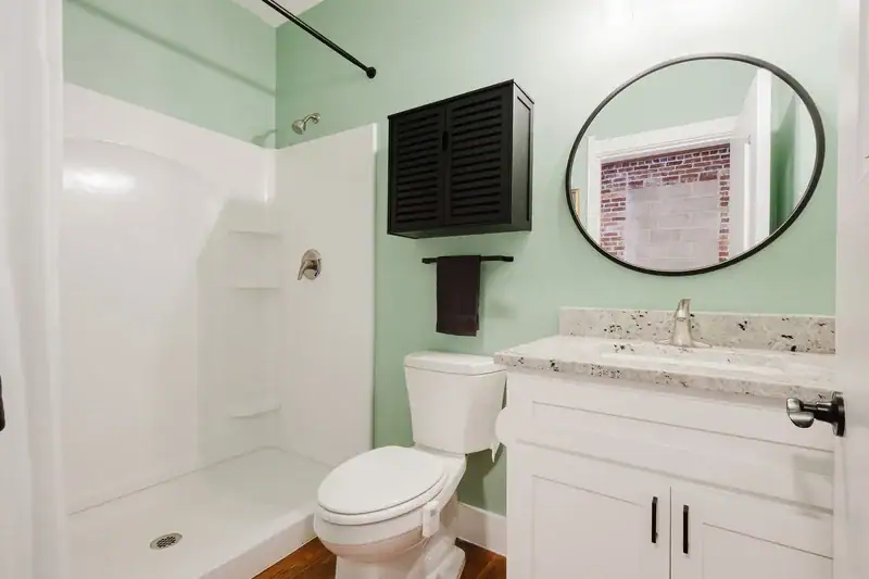Apartment 303 bathroom with walk-in shower and round mirror