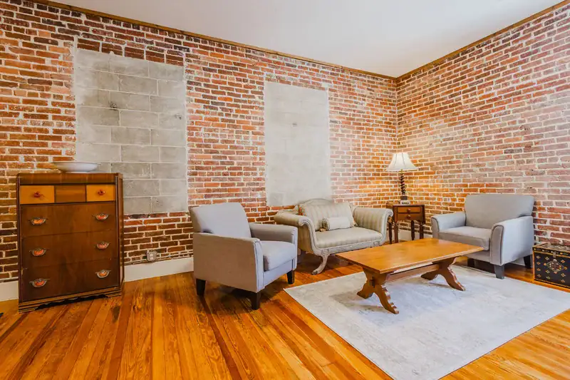 Apartment 303 sitting area with armchairs, coffee table and exposed brick