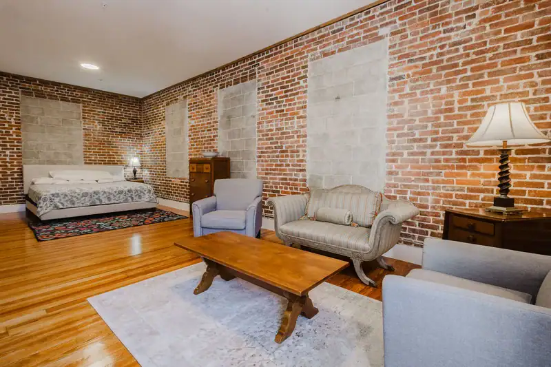 Apartment 303 sitting area with sofa, armchairs and bed beyond