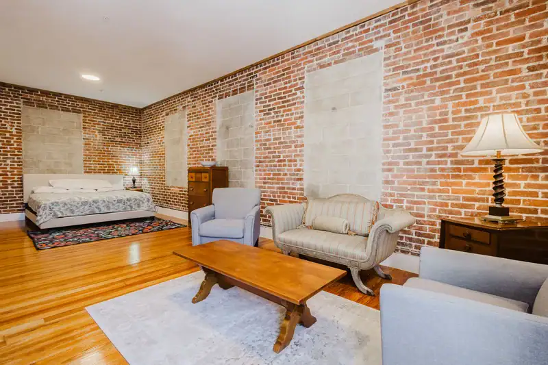 Apartment 303 bedroom with seating area and exposed brick walls